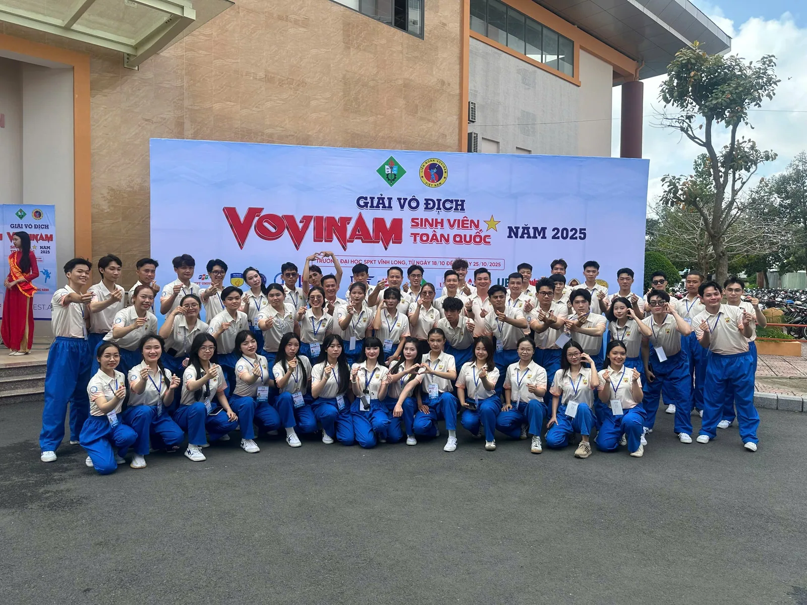 Đông người mặc võ phục xanh chụp ảnh cùng nhau ngoài trời