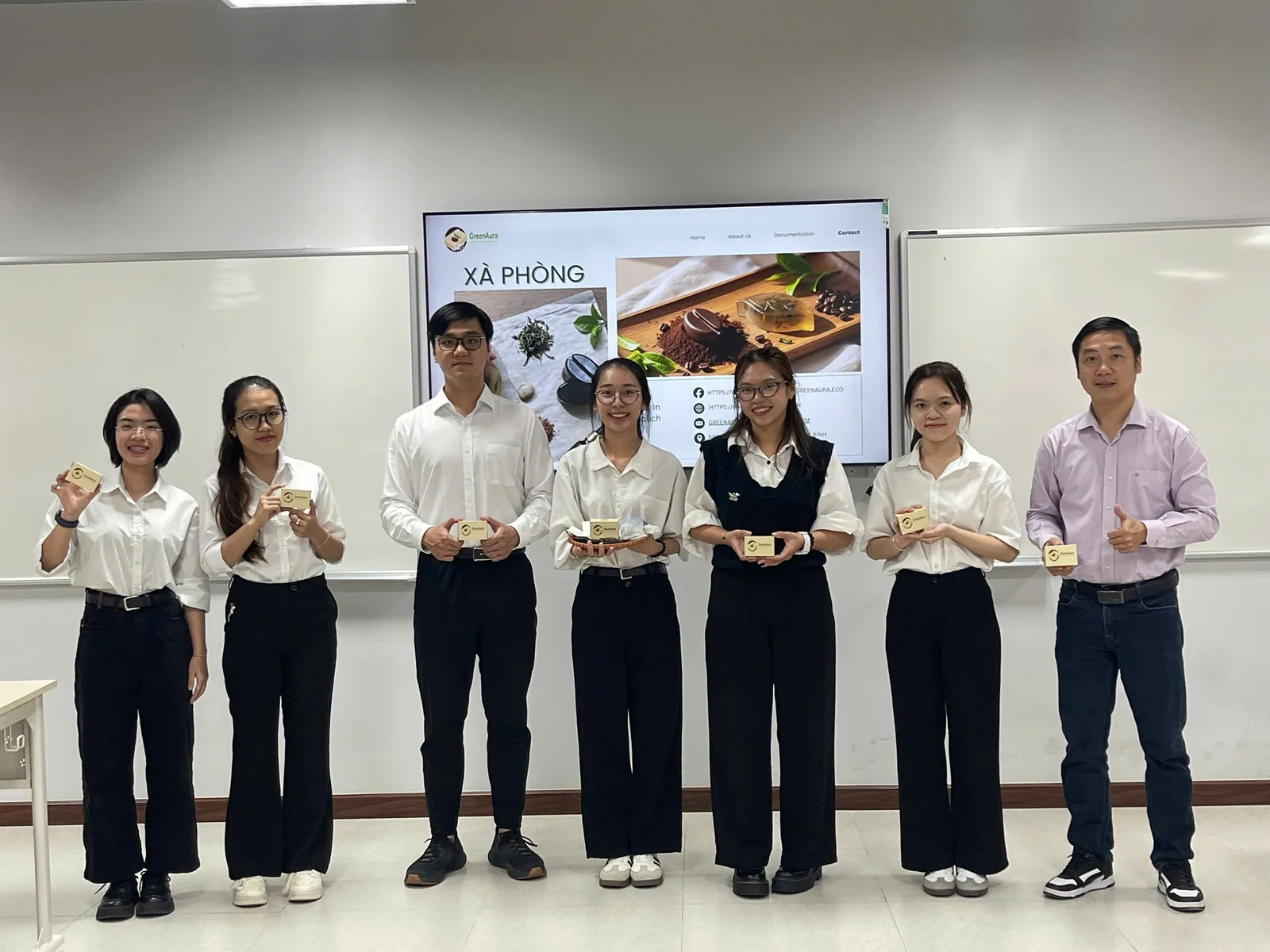 Nhóm sinh viên chụp ảnh trước bảng và màn hình trong lớp